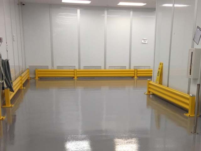 Gray epoxy manufacturing floor with yellow safety guard rails